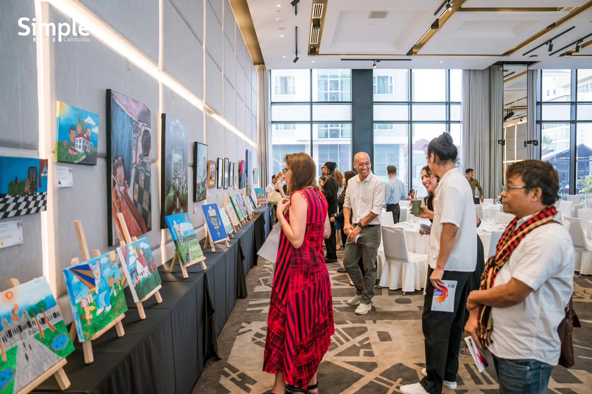 Exhibition hall with paintings on easels and visitors